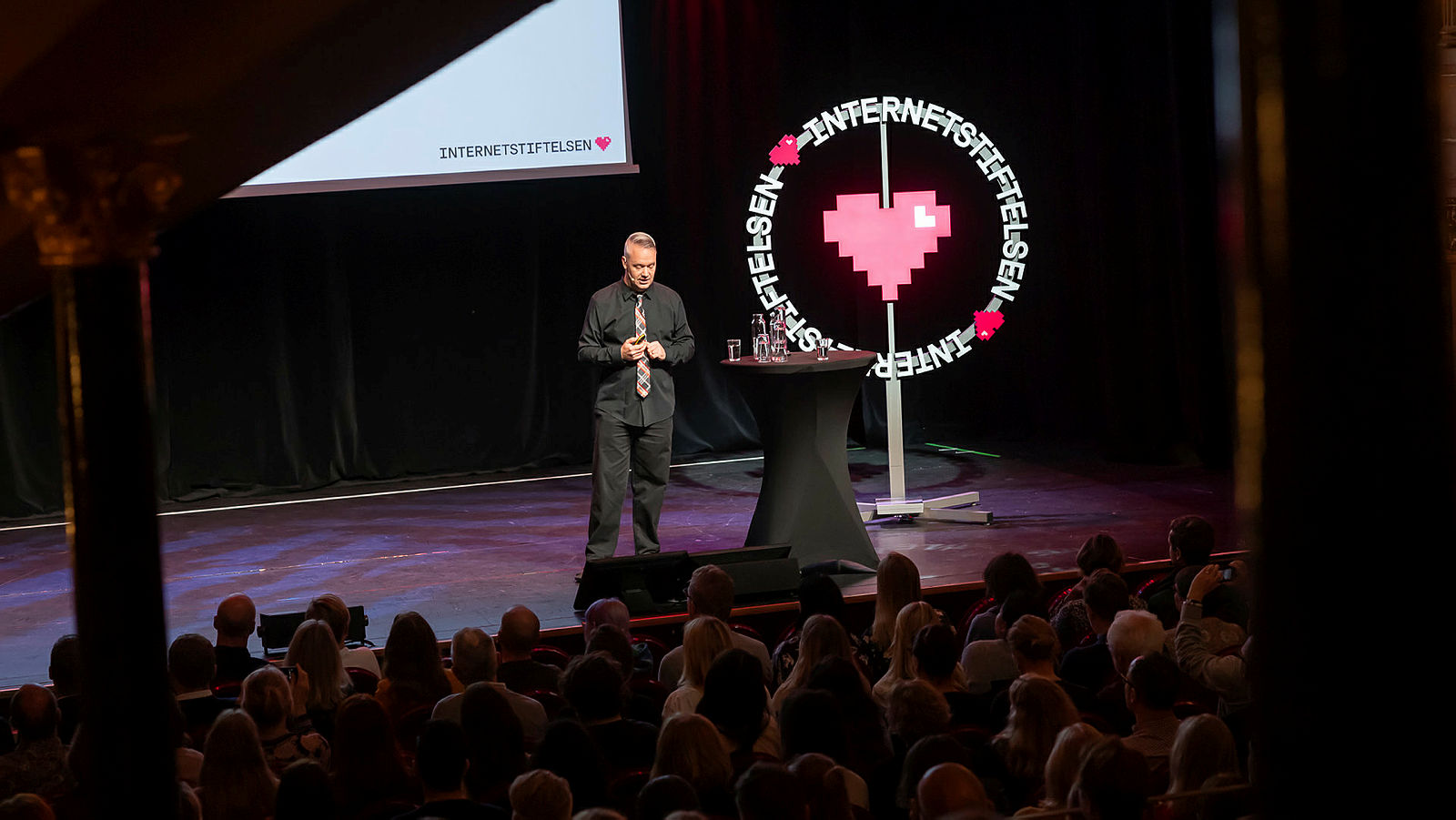 Måns Jonasson står på en scen och presenterar Svenskarna och internet 2019.