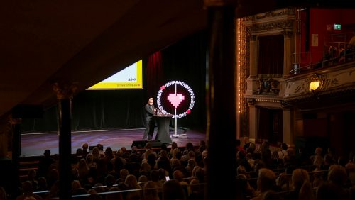 Måns Jonasson står på en scen och presenterar Svenskarna och internet 2019.