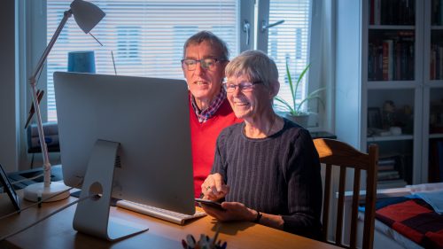 Äldre par sitter framför datorn och arbetar tillsammans