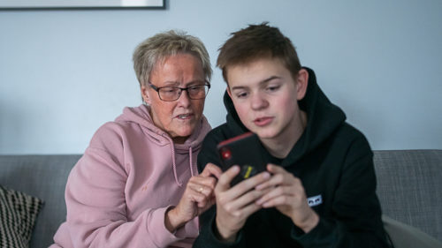 Pojke visar äldre kvinna något på sin mobiltelefon
