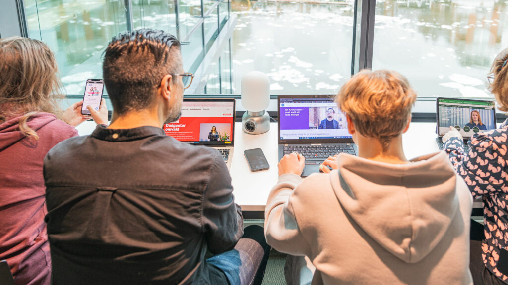 Personer sitter i rad framför datorer med politisk information.