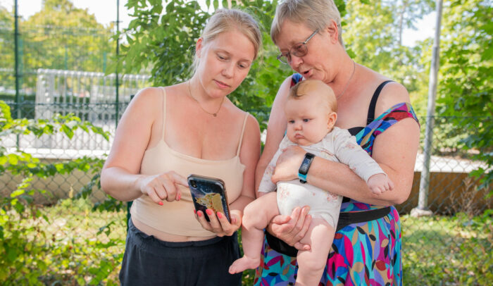 Tre generationer tittar på en mobil.
