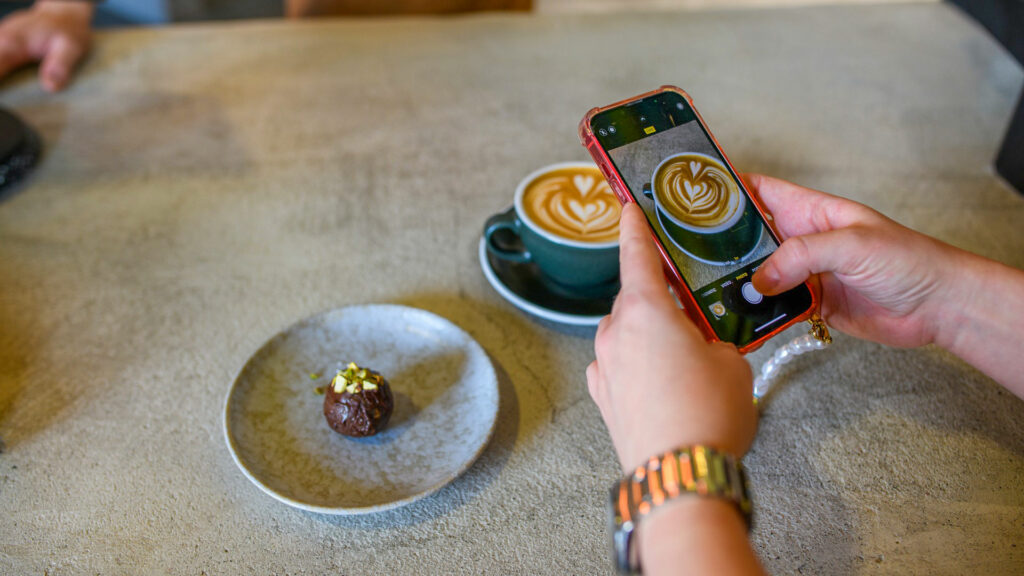 Instagram i Sverige. Händer som håller upp mobilkamera för att ta en bild på fika.
