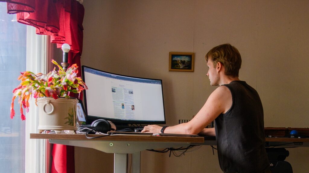 En man står vid ett upphöjt skrivbord och tittar på sin dator, på skärmen syns Wikipedia. 