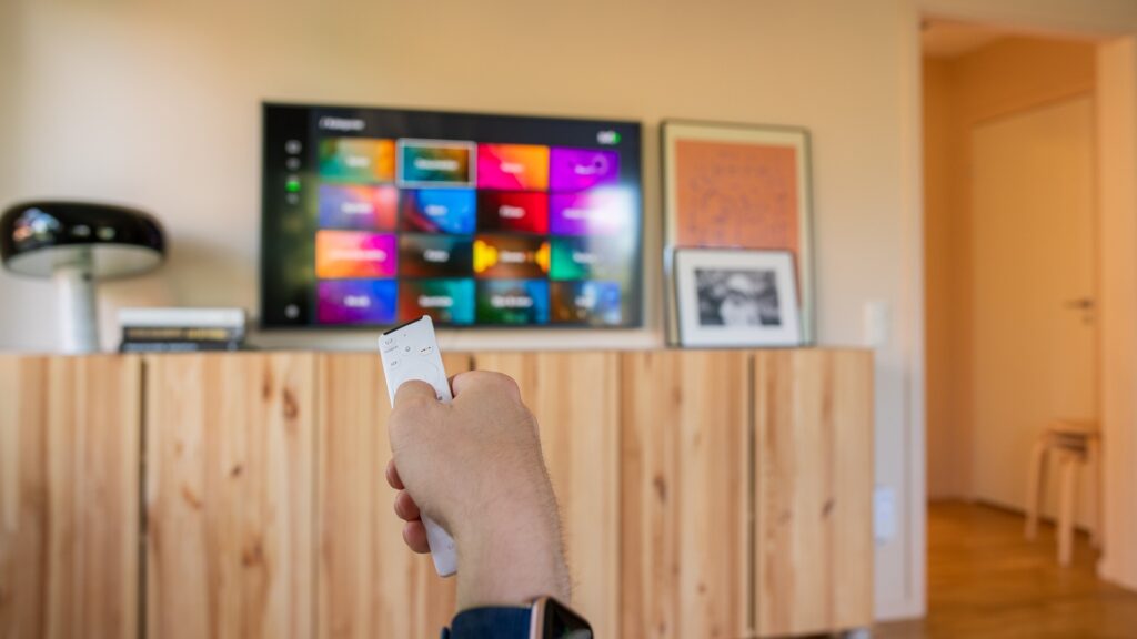 En hand håller upp en fjärrkontroll till tv:n, på tv:n i bakgrunden syns SVTPlay.