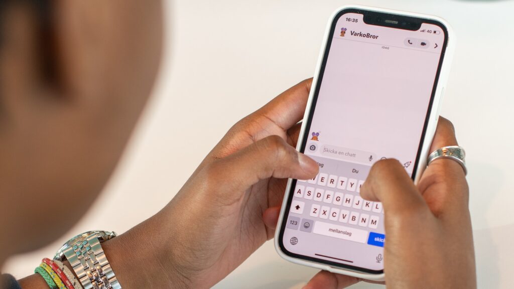 Ungdom som håller en mobil, på skärmen syns en chatt på Snapchat.