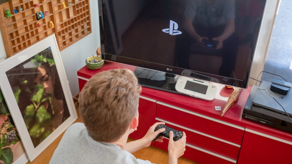 Ett barn som sitter framför tv:n och spelar Playstation, gaming, dataspel.