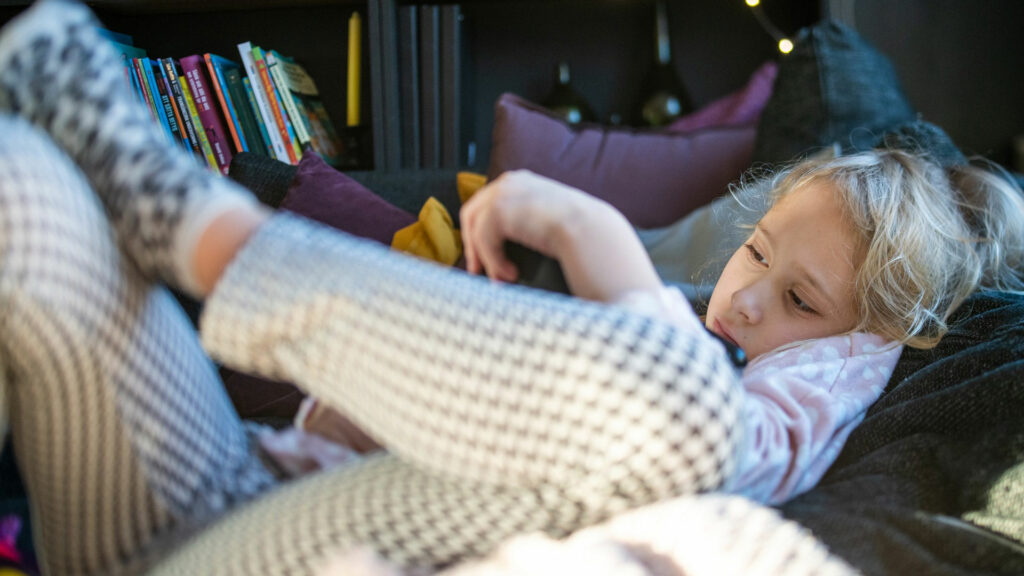 Ett barn ligger i en soffa och läser.