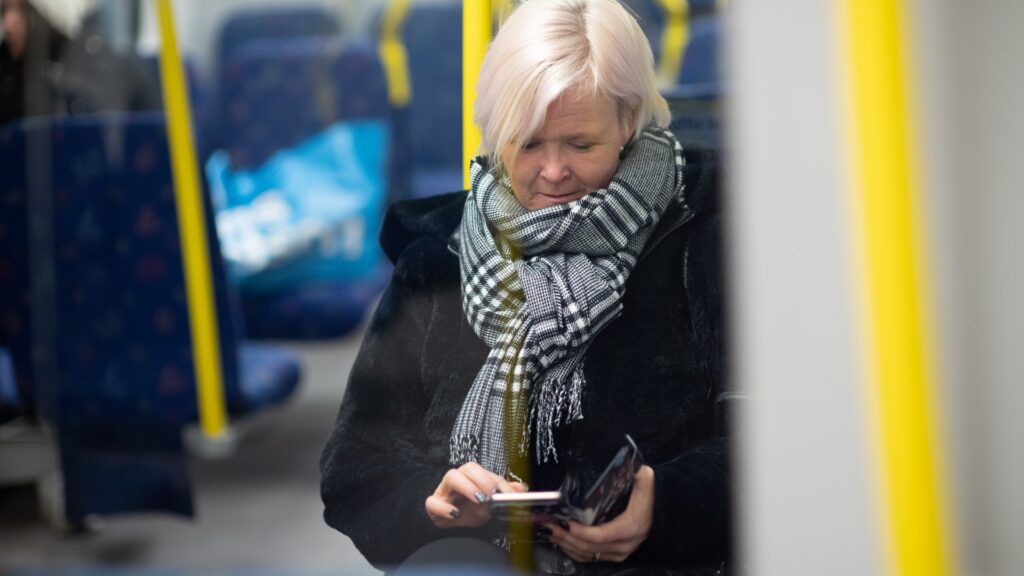 Kvinna använder mobiltelefon i tunnelbanevagn.