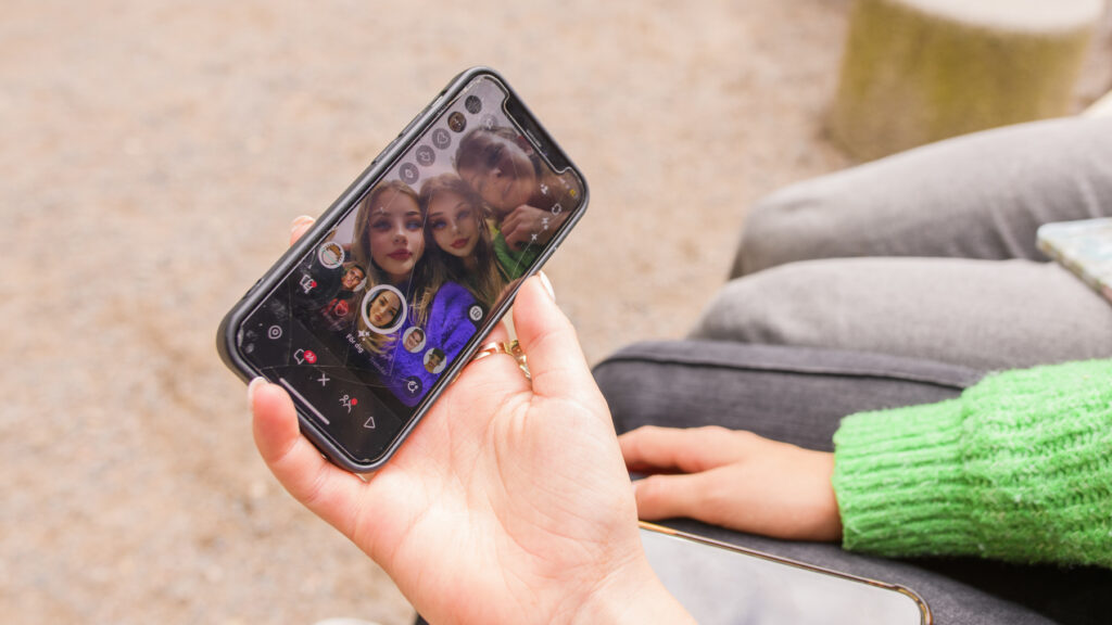 Tre tjejer använder AI-filter i mobilen.