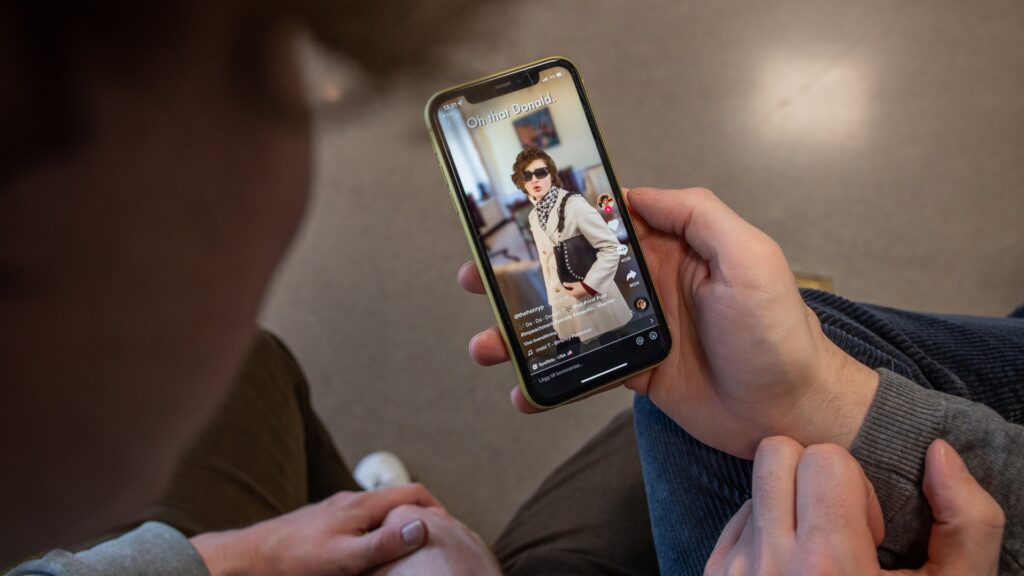 En man som håller i en mobiltelefon med en bild på en kvinna på Tiktok.