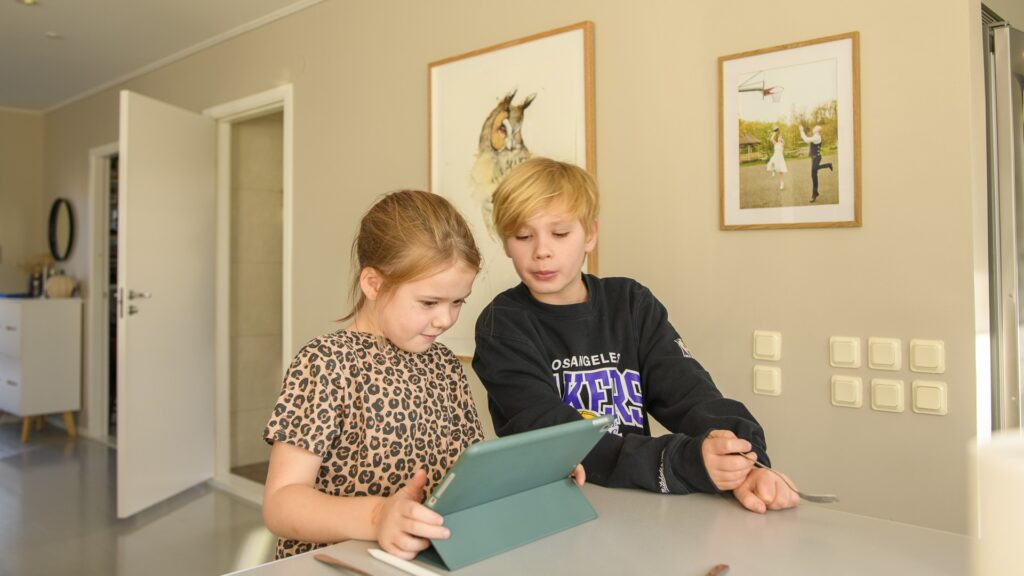 Några barn som sitter vid ett bord och spelar Roblox.