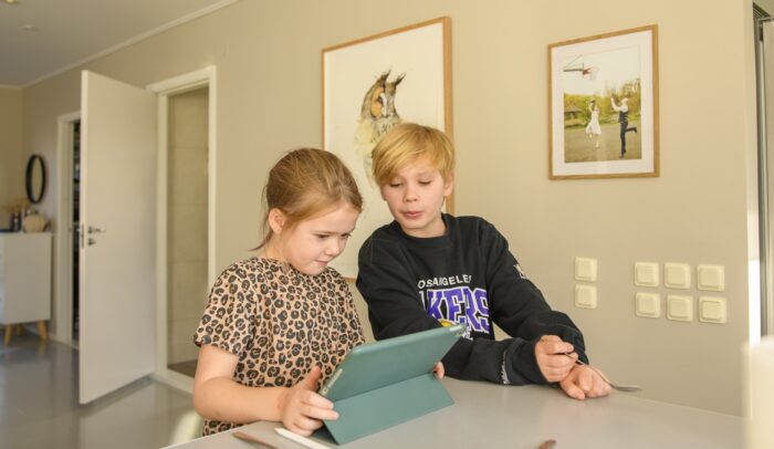 Några barn som sitter vid ett bord och spelar Roblox.