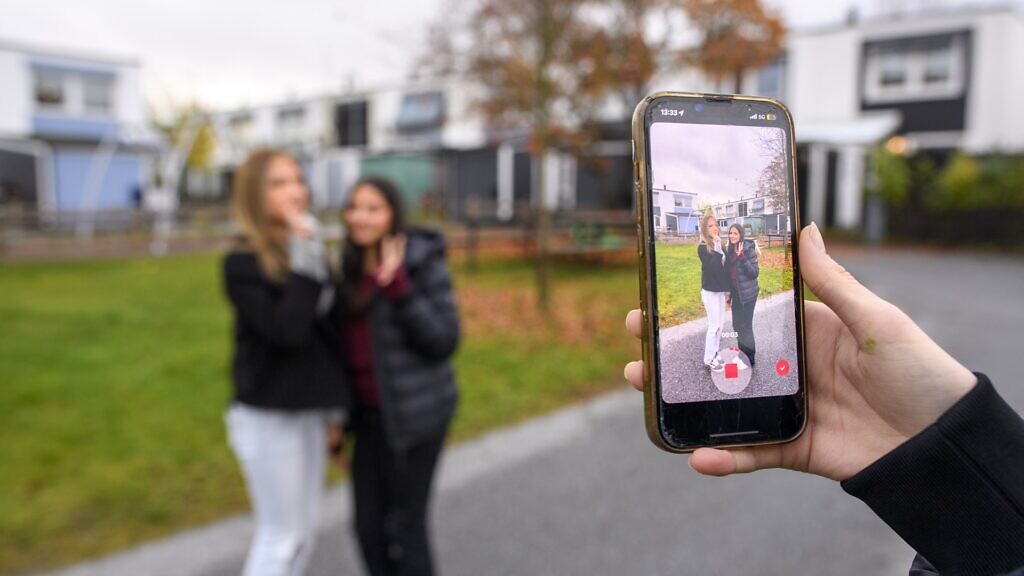 En tjej som tar en bild av sina kompisar med mobilen.