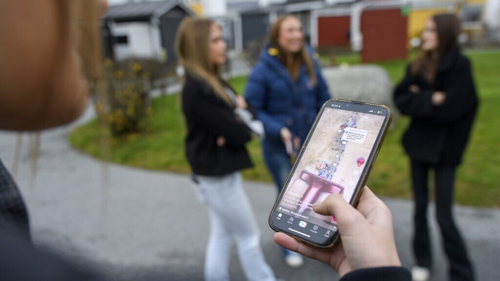 En person som håller upp en mobiltelefon framför en grupp människor.