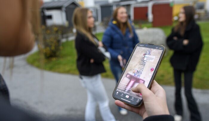 En person som håller upp en mobiltelefon framför en grupp människor.