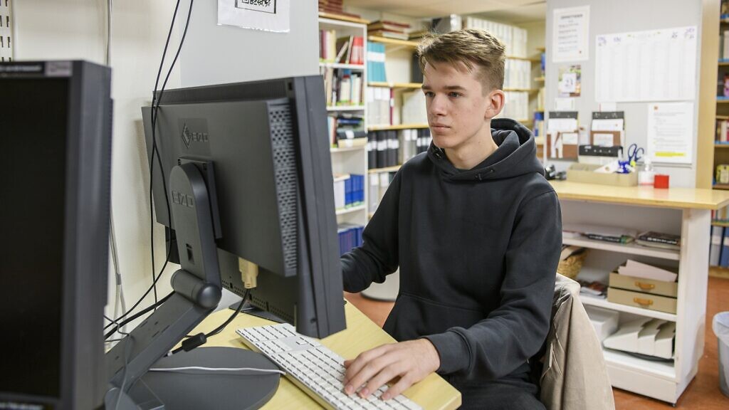 En ung man som sitter framför en datorskärm.