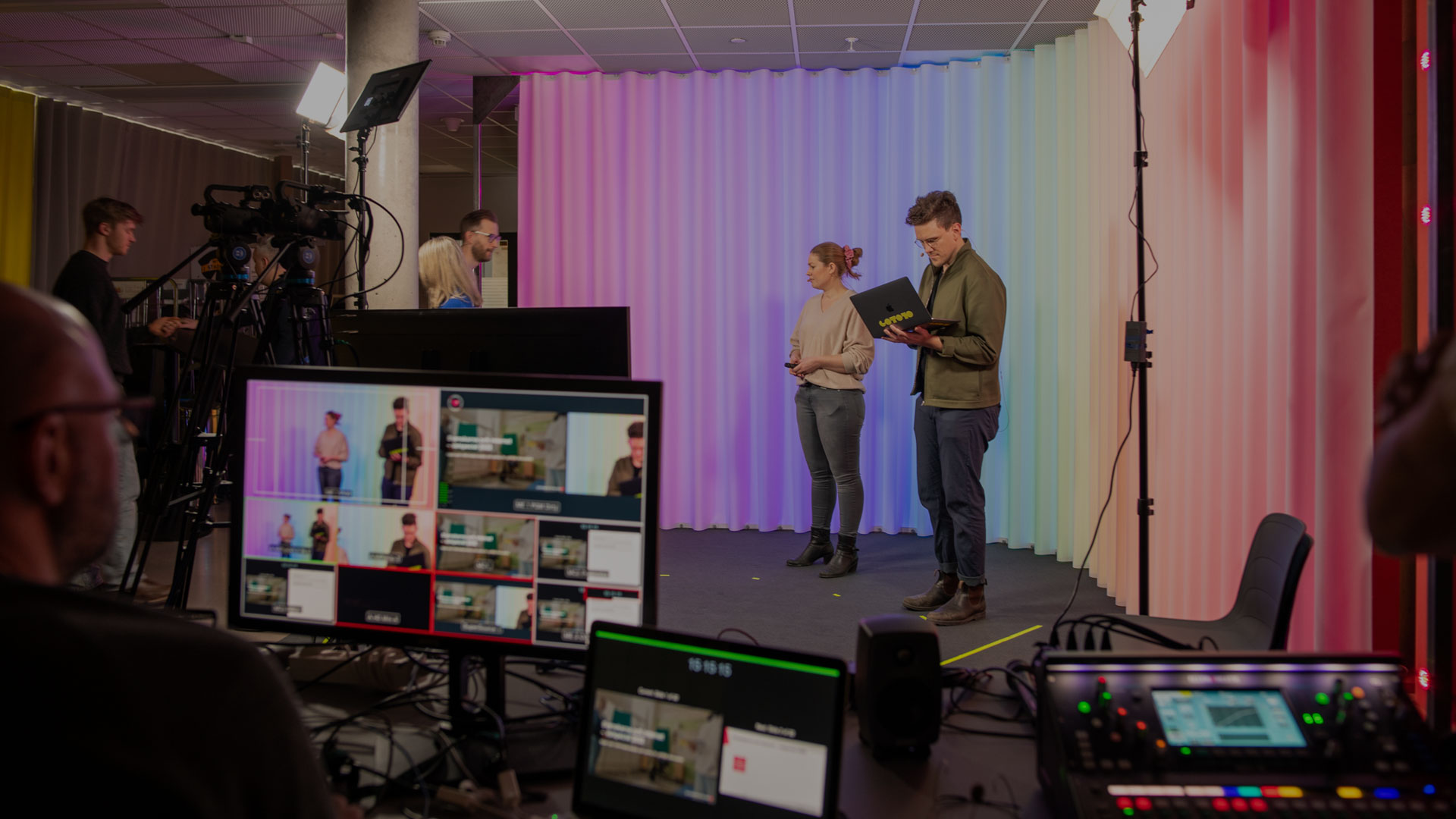 Några personer står på en scen framför en kamera.