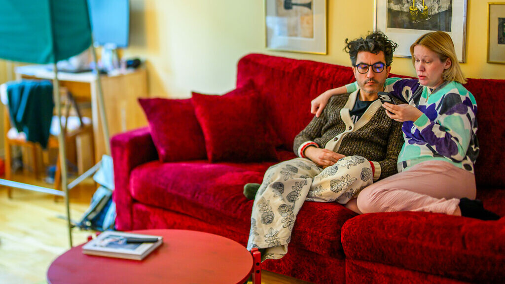 En man och en kvinna sitter i en soffa och tittar på en mobil tillsammans.