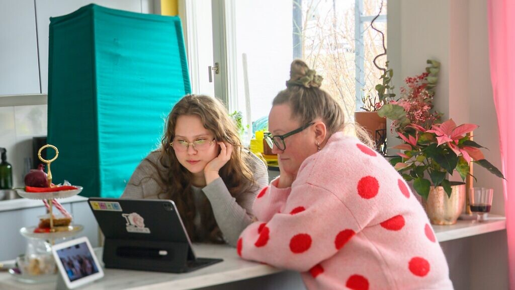 Två kvinnor sitter vid ett bord med en bärbar dator.