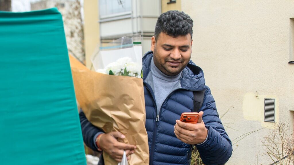 En man i blå jacka tittar på sin mobiltelefon.