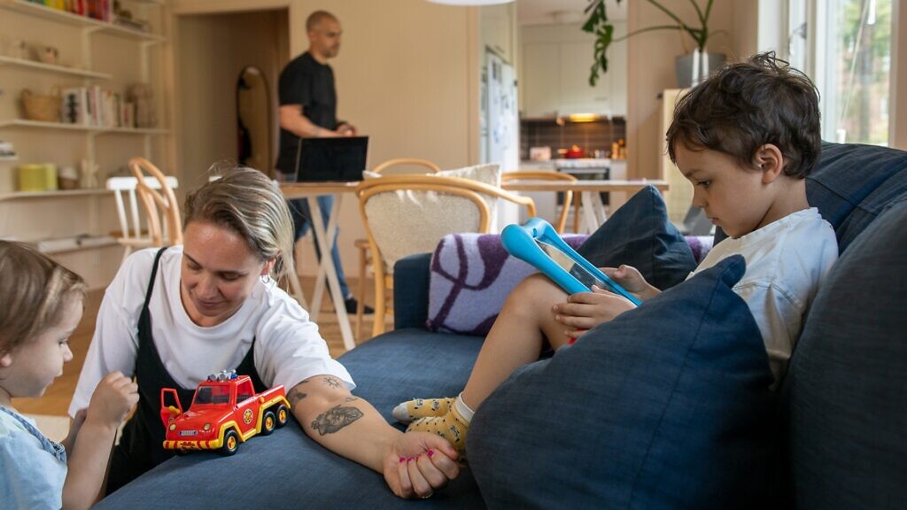 En kvinna sitter i en soffa med två barn.