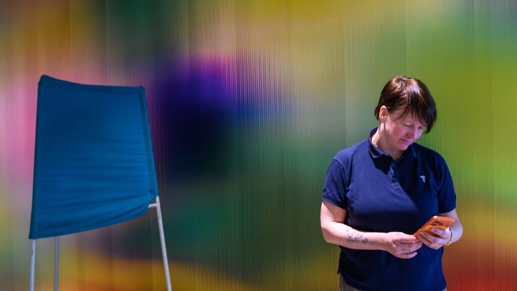 En kvinna som står bredvid en valskärm och diskuterar politik på nätet.