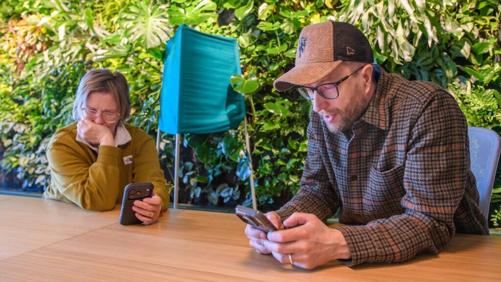 En man och en kvinna sitter vid ett bord och tittar på en mobiltelefon.