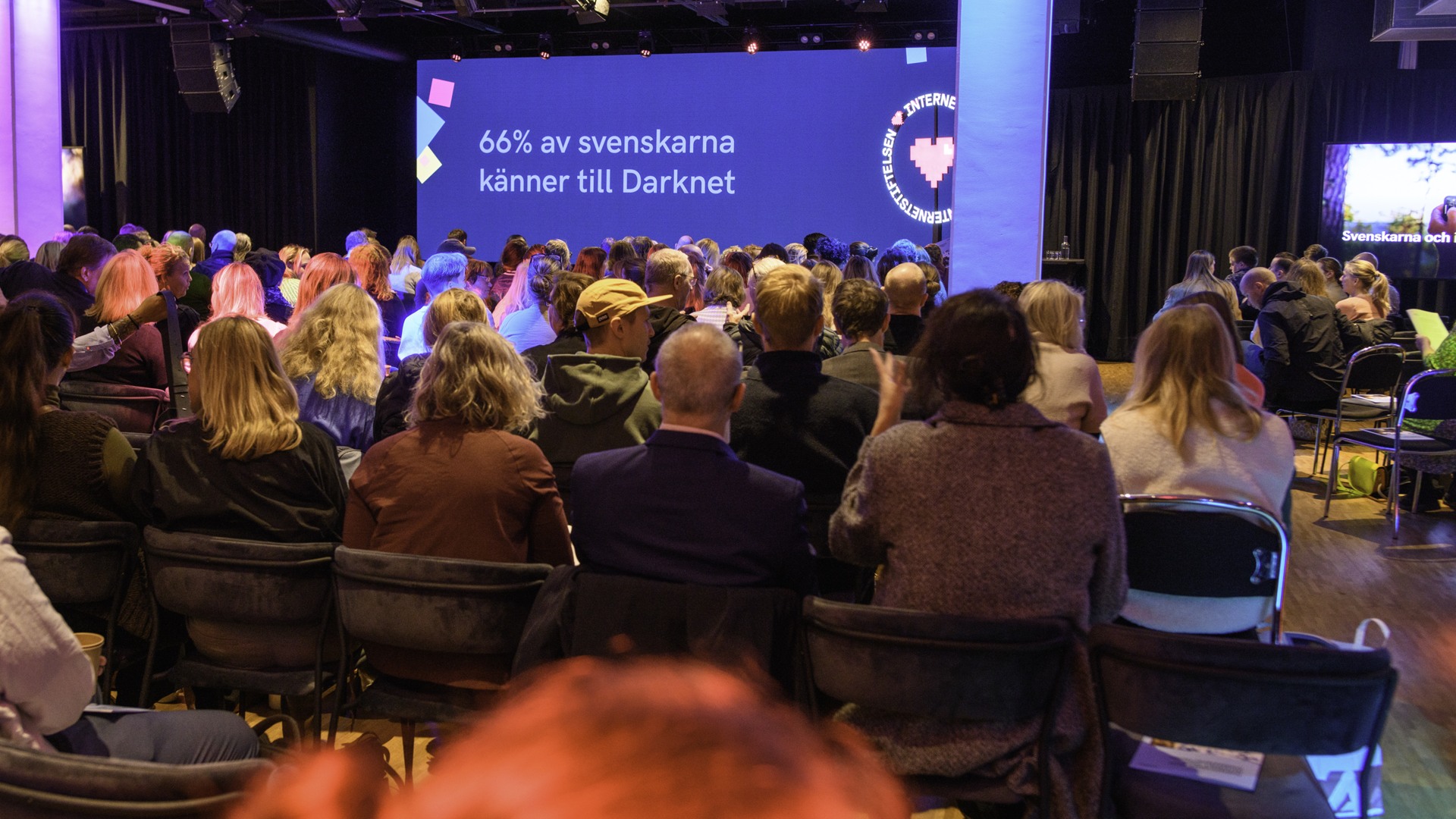 En grupp människor som sitter på stolar framför en scen.