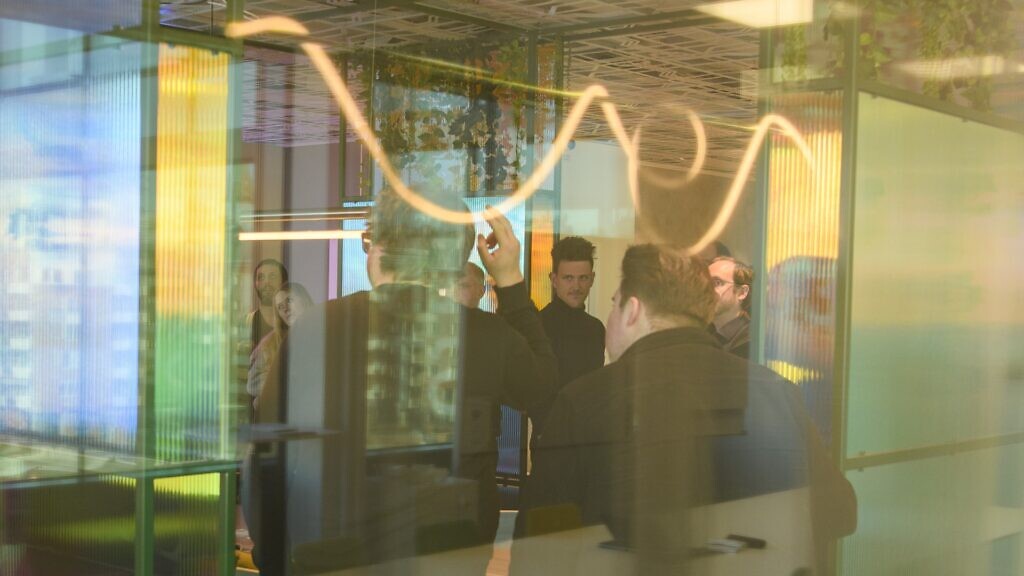 Neonlampor i taket över en grupp män.