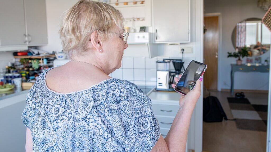En kvinna som håller en mobiltelefon i ett kök.