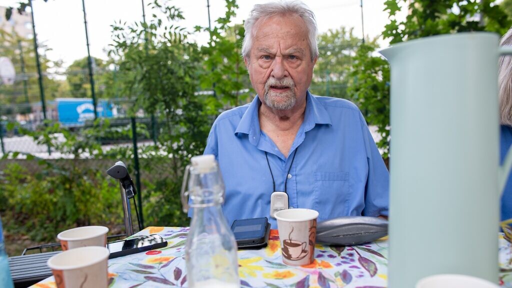 En man som sitter vid ett bord med en kopp kaffe.