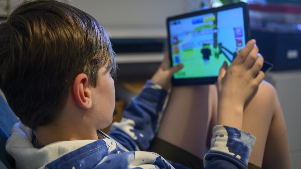 En liten pojke som sitter i en stol och spelar Roblox.