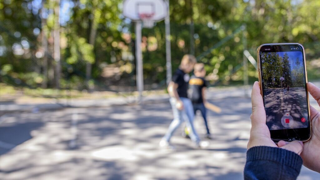 En person som håller upp en mobiltelefon för att ta en bild.